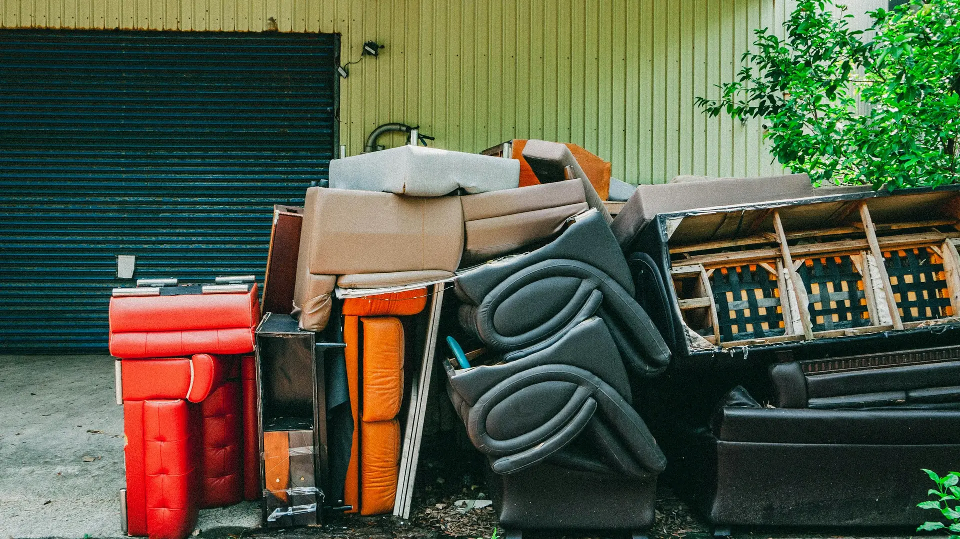 Old furniture, chairs and boxes piled in front of a garage door