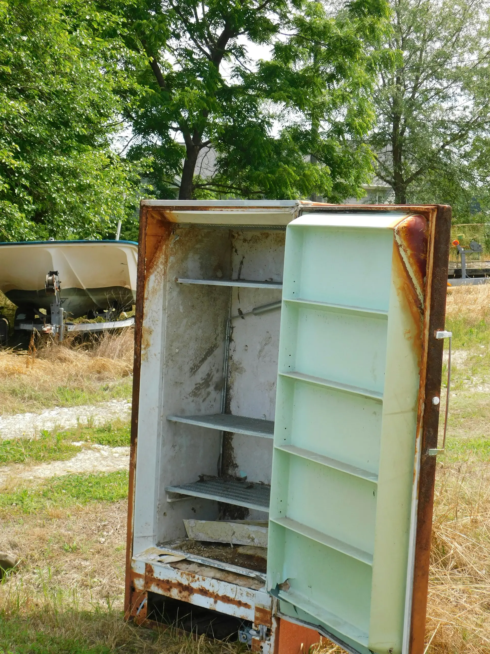An old rusty refrigerator standing in the grass